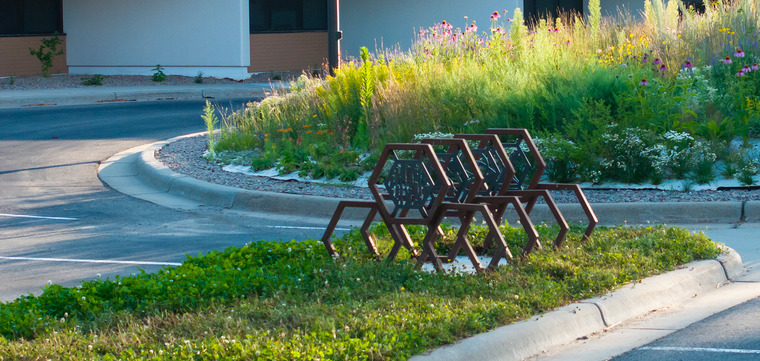 Metal hexagons assembled in four groups of three to form a bike rack, with art panels in the top hexagon of each group.